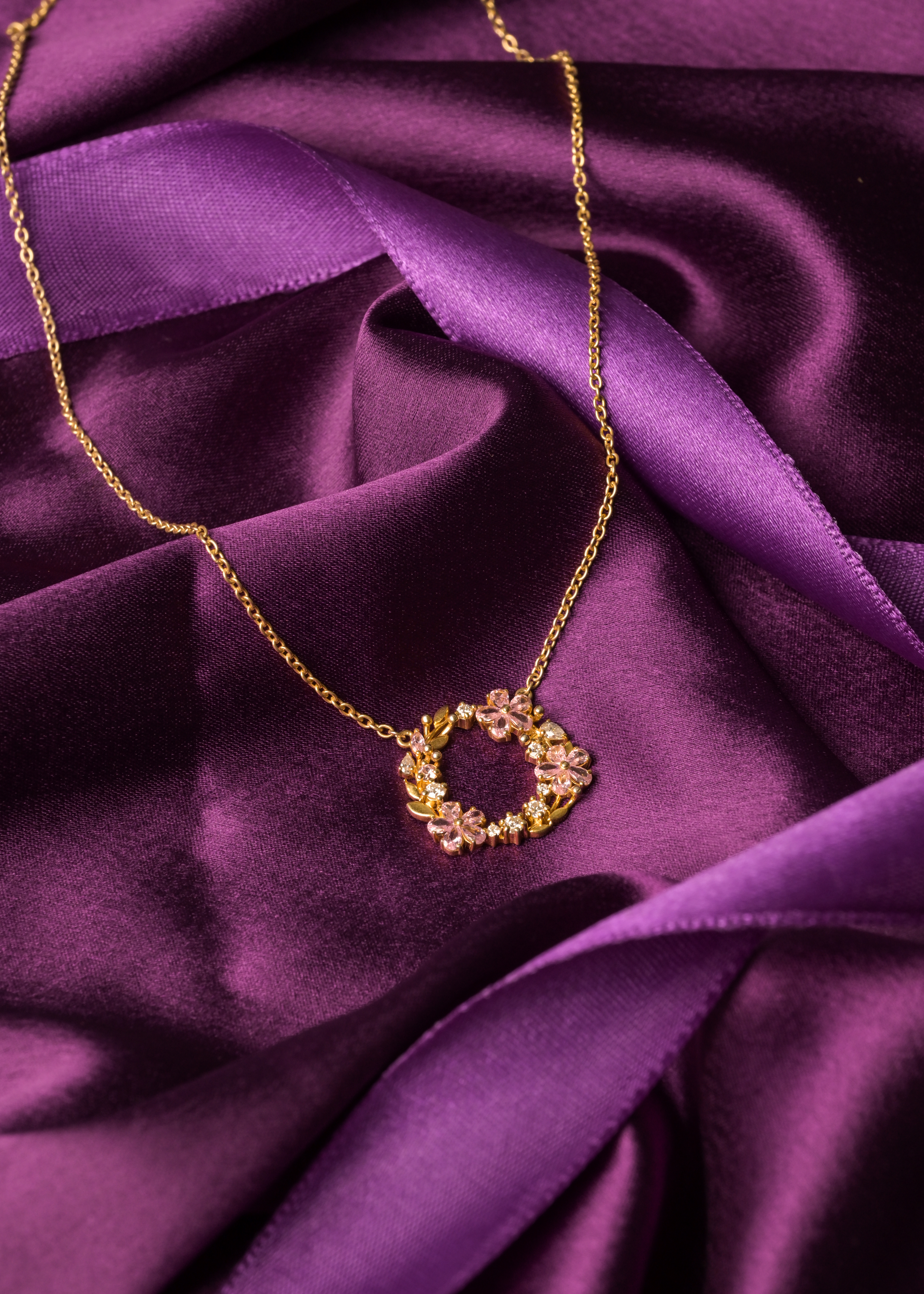 Gold floral pendant photographed on rich purple fabric